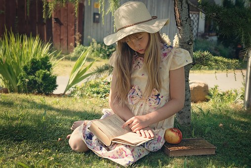 Girl sitting in garden reading book by Meria Chand